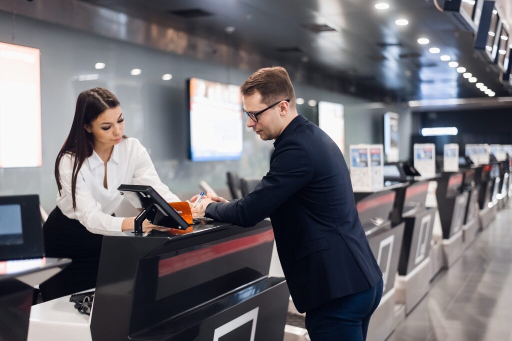 man with woman check in counter airport standby discussion